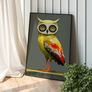 May include: Framed art print featuring a stylized owl with yellow, red, and orange plumage. The owl has large, concentric circle eyes and orange legs. The artwork is set against a gray background.