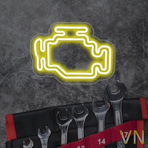 May include: A yellow neon sign shaped like the car engine light symbol. The sign is on a grey textured background.