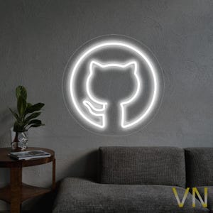 Könnte beinhalten: Ein weißes Neon-Schild mit einem Kreis um einen stilisierten Katzenkopf, die Katze blickt auf die linke Seite des Bildes. Das Schild ist an einer grauen Wand über einem grauen Sofa angebracht.