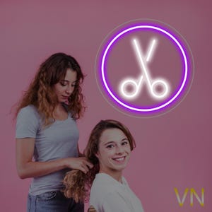 Puede incluir: Dos mujeres, una peinando el cabello de la otra. La mujer de la derecha sonríe a la cámara. Un letrero de neón de tijeras en un círculo está en el fondo. El fondo es rosa.