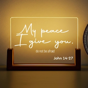 May include: A rectangular LED night light with the text "My peace I give you. do not be afraid John 14:27" in a handwritten style. The light is set in a dark brown wooden base.