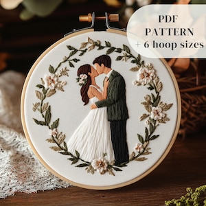 May include: Embroidered hoop art depicting a kissing couple, framed by a floral wreath. The couple is in wedding attire. The text "PDF PATTERN + 6 hoop sizes" is displayed. The embroidery is set in a wooden hoop, a popular craft item.