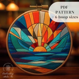 May include: A colorful embroidery hoop featuring a sunset design with vibrant hues of orange, red, blue, and green. The text "PDF PATTERN + 6 hoop sizes" is displayed. The wooden hoop is round and the embroidery is hand-stitched.