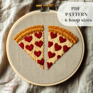 Puede incluir: Bordado de dos porciones de pizza con corazones rojos. La corteza es de color amarillo dorado y la base es de color beige claro. El texto "PDF PATTERN + 6 hoop sizes" es visible. Presentado en un bastidor de madera.