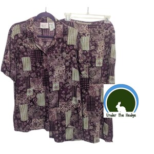 May include: A two-piece matching set consisting of a short-sleeved button-down shirt and a skirt, both featuring a dark purple and light beige patchwork pattern with floral and geometric motifs. The set is displayed on two separate hangers.