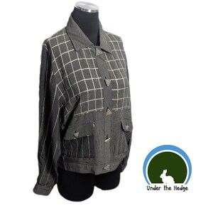 May include: A gray jacket with a grid pattern on the front and a striped pattern on the sleeves. The jacket has a collar, pockets, and triangle-shaped buttons. The jacket is displayed on a mannequin.