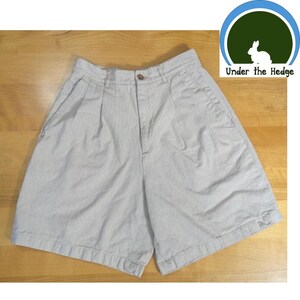 May include: Light beige seersucker shorts with a button closure and front pleats. The shorts have two front pockets and a classic, casual design. The shorts are made of a lightweight fabric, perfect for warm weather. The shorts are from Under the Hedge.