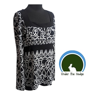 May include: A long-sleeved top featuring a black and white repeating scroll pattern, a solid black square neckline, and a solid black empire waist band. The garment is displayed on a mannequin. A logo with a white rabbit and the text Under the Hedge.