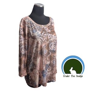 May include: A long-sleeved top with a scoop neck, displayed on a mannequin. The top features a paisley pattern in shades of brown, beige, and blue. The design is intricate and covers the entire garment. The brand logo "Under the Hedge" is visible.