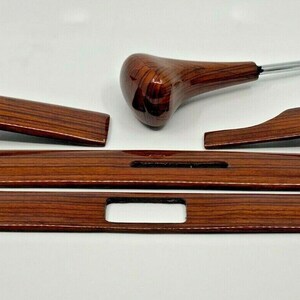 Puede incluir: Un conjunto de cinco piezas de moldura interior de automóvil de imitación de madera, que incluyen una perilla de cambio de marchas, dos paneles largos y dos paneles cortos.