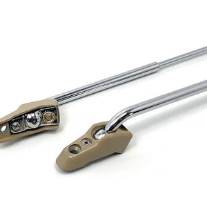 May include: Two chrome car sun visor arms with beige plastic ends. The arms are extended and the ends are facing the camera.