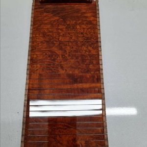 Op de afbeelding: Een houten lattenbak met een bruine houten afwerking en een handvat. De bak heeft een zilveren strip aan de onderkant.