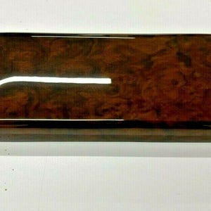 May include: A dark brown woodgrain car interior trim piece with a glossy finish.