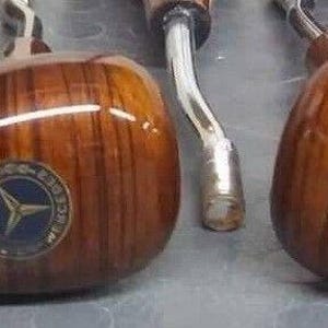 Puede incluir: Cinco pomos de cambio de marchas de madera con un logotipo de estrella en el centro. Los pomos son marrones con un patrón de veta de madera y tienen una base de metal plateado.