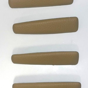 May include: Four beige leather door handles for a car.
