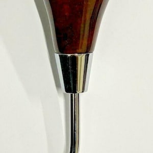 May include: A brown wood gear shift knob with a chrome base and a chrome extension.