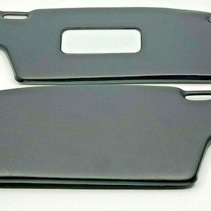 May include: Two black car sun visors with a small rectangular window in the top visor.