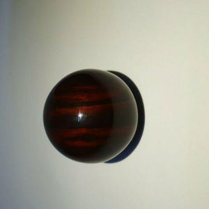 Könnte beinhalten: Eine dunkelbraune und schwarz gestreifte Kugel mit glänzender Oberfläche.