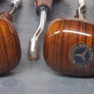 May include: Five wooden gear shift knobs with a silver star logo. The knobs are brown with a wood grain pattern.