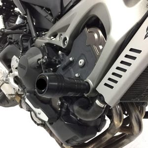 May include: Black motorcycle frame sliders installed on a silver and black motorcycle engine. The sliders are cylindrical and designed to protect the motorcycle's fairing and engine components in the event of a fall. The Yamaha logo is visible on the engine.