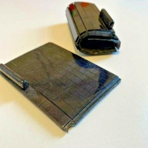 Op de afbeelding: Twee zwarte rubberen stempels met een rasterpatroon. De stempels zijn rechthoekig en hebben een licht gebogen vorm.