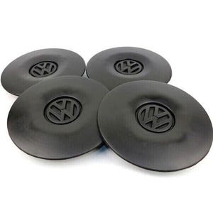 Puede incluir: Conjunto de cuatro tapacubos de plástico negro con el logotipo de Volkswagen en el centro.