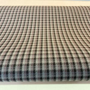 May include: Close-up of a fabric with a classic checkered pattern. The fabric features a grid of small squares in shades of black, grey, and a muted blue-grey. The pattern is evenly spaced and creates a textured appearance.