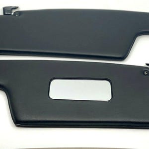 May include: A pair of black car sun visors with a vanity mirror on one visor.