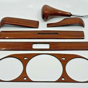 Könnte beinhalten: Ein Satz von sechs Holzmaserung-Armaturenbrett-Verkleidungsteilen für ein Auto. Die Teile sind in verschiedenen Formen und Größen und alle aus dunkelbraunem Holz.