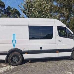 May include: White van with black wheel arches and black trim around the windows. The van has a sliding door on the passenger side and a large rear door.