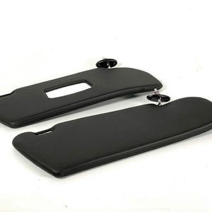 Puede incluir: Un par de viseras para el sol de coche negras con un clip en el lateral.