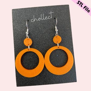 May include: A pair of orange hoop earrings with a smaller circle attached to the top of each hoop. The earrings are on a black card with the word "cholleet" written on it.