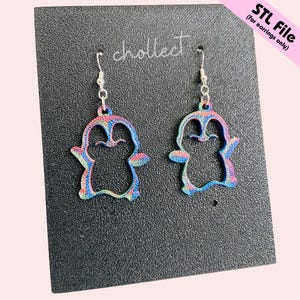 May include: A pair of penguin-shaped earrings with a colourful, rainbow-like pattern. The earrings are hanging from silver-coloured hooks. The text "STL File (for earrings only)" is visible in the upper right corner. The word "chollect" is also visible.