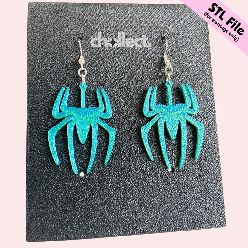 May include: A pair of teal spider-shaped earrings with silver hooks. The earrings have a glittery finish and are displayed on a textured black surface. The text "chcollect" is visible. The upper right corner has the text "STL File (for earrings only)".