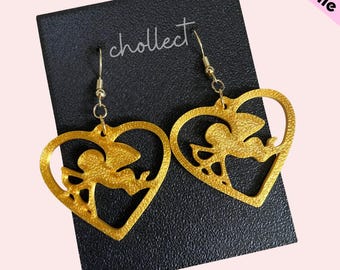 May include: Gold-colored heart-shaped earrings with a cutout design of a cupid holding an arrow. The earrings are on a black background with the word "cholleect" written in white.