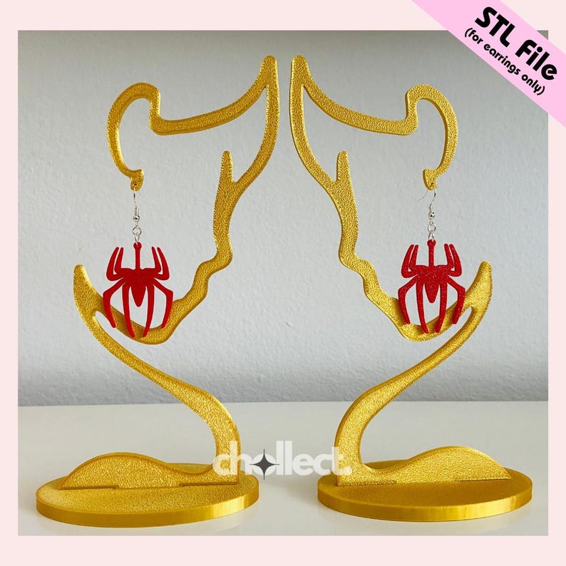 May include: Gold-colored earring display stands holding red spider-shaped earrings. The stands have a unique, artistic design with a circular base and curved upper portion. The text "STL File (for earrings only)" is in the upper right corner.