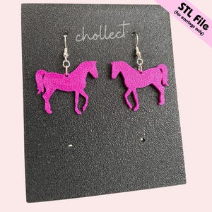 May include: A pair of magenta horse-shaped earrings hanging on a black display card. The earrings are made of a textured material and have silver-colored hooks. The card has the word "chollect" in cursive and the text "STL File (for earrings only)".