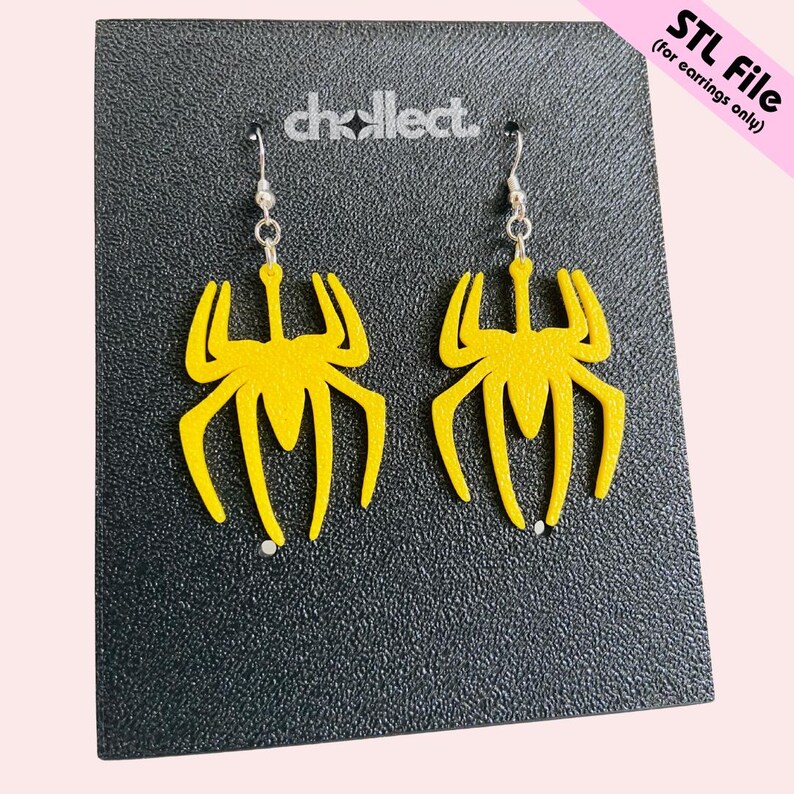 May include: A pair of yellow spider-shaped earrings with silver hooks. The earrings are displayed on a black textured surface with the text "STL File (for earrings only)". The brand name "chollect." is also visible.