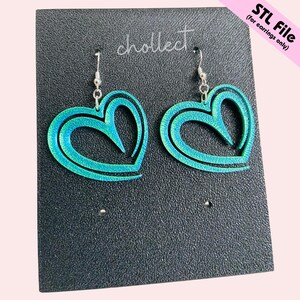 Puede incluir: Pendientes en forma de coraz&oacute;n de color turquesa con acabado brillante. Se exhiben sobre una superficie negra texturizada. El texto "cholllect" y "STL File (for earrings only)" son visibles.