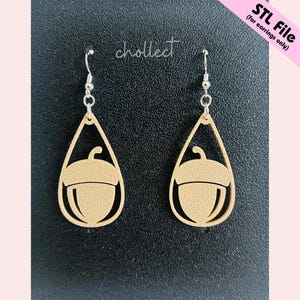 May include: A pair of beige acorn-shaped earrings with silver hooks. The earrings are cut out with a teardrop shape and feature the word "chollect" in cursive. The text "STL File (for earrings only)" is in the upper right corner.
