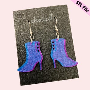 May include: A pair of dangle earrings featuring a blue and purple boot design. The boots have a pointed toe and a high heel. The earrings are made of a shiny, metallic material.