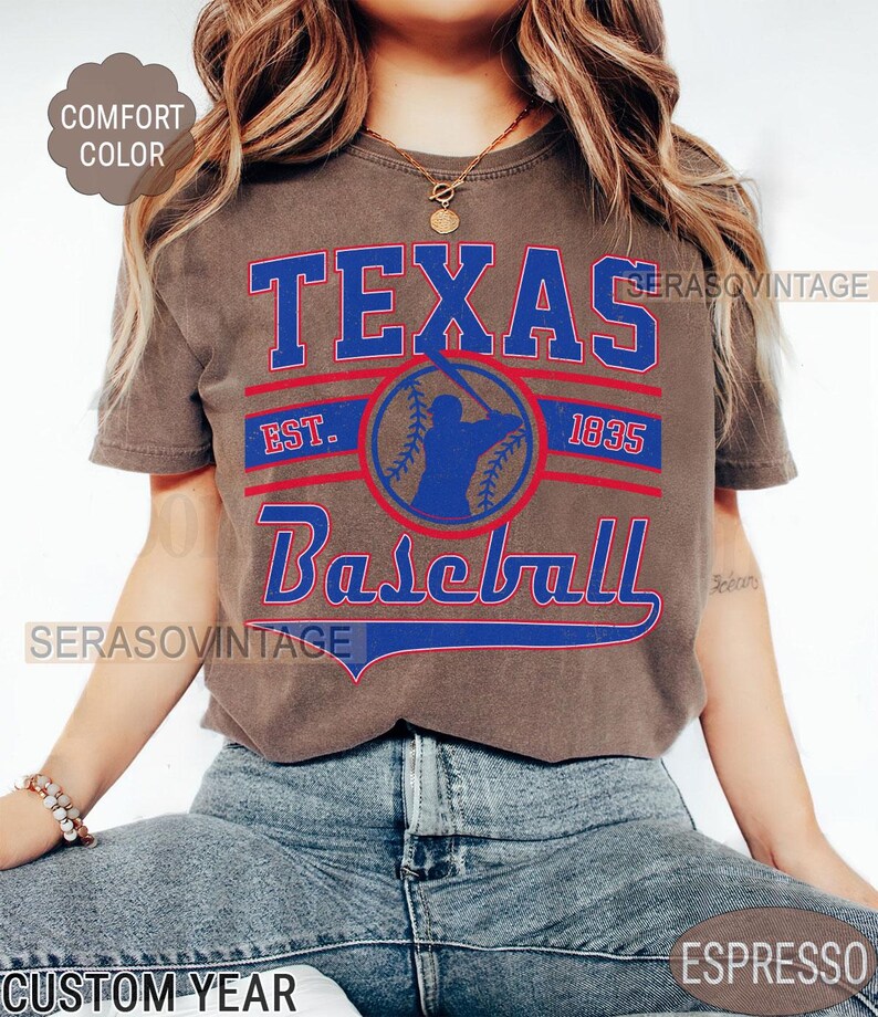 Pode incluir: Uma camiseta marrom com um design gr&aacute;fico de estilo vintage que apresenta o texto "Texas Baseball" com uma silhueta de jogador de beisebol e o texto "Est. 1835".
