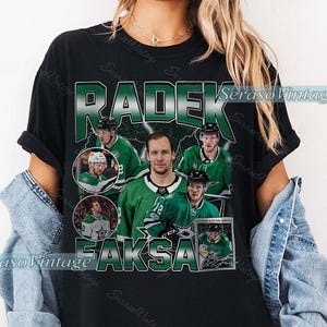 Może przedstawiać: Czarna koszulka z kolażem hokeisty Radka Faksy w zielono-białym stroju. Koszulka zawiera napis "RADEK FAKSA" w zielono-białym wzorze z logo SerasoVintage.