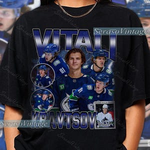 May include: Black t-shirt featuring a collage of hockey player Vitali Kravtsov in a blue and white uniform. The design includes the player's name and the text "KRAVTSOV" in a blue and white font. The shirt has a vintage aesthetic.
