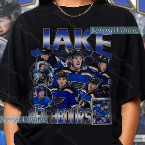 Op de afbeelding: Zwart T-shirt met een hockeythema. Het heeft een collage van spelers in blauw en geel, met de naam "JAKE" in blauw erboven en "NEIGHBOURS" eronder. Het ontwerp heeft een vintage stijl.