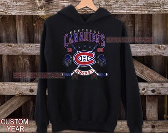 Puede incluir: Sudadera con capucha negra con un logotipo de hockey de los Montreal Canadiens, las palabras "Montreal Canadiens Hockey" y los números "19" y "09".
