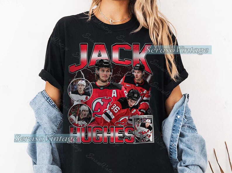 May include: Black t-shirt featuring a vintage-style design with the name "JACK HUGHES" in red and white. The shirt includes images of a hockey player in a red and black uniform. The text "SerasoVintage" is also visible.
