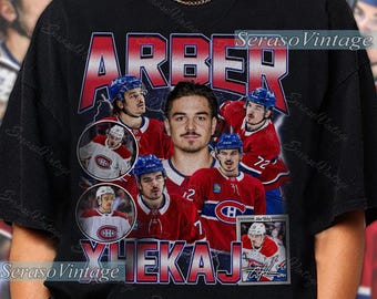 Puede incluir: Camiseta negra con un collage de imágenes de un jugador de hockey con uniforme rojo y azul. El nombre "ARBER" está impreso en letras rojas grandes sobre la imagen del jugador. El nombre "XHEKAJ" está impreso en rojo debajo.