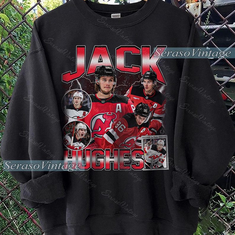 May include: Black sweatshirt featuring a graphic of hockey player Jack Hughes. The design includes the name "JACK" in red block letters, player images, and the name "HUGHES" in red. The team logo is also visible.