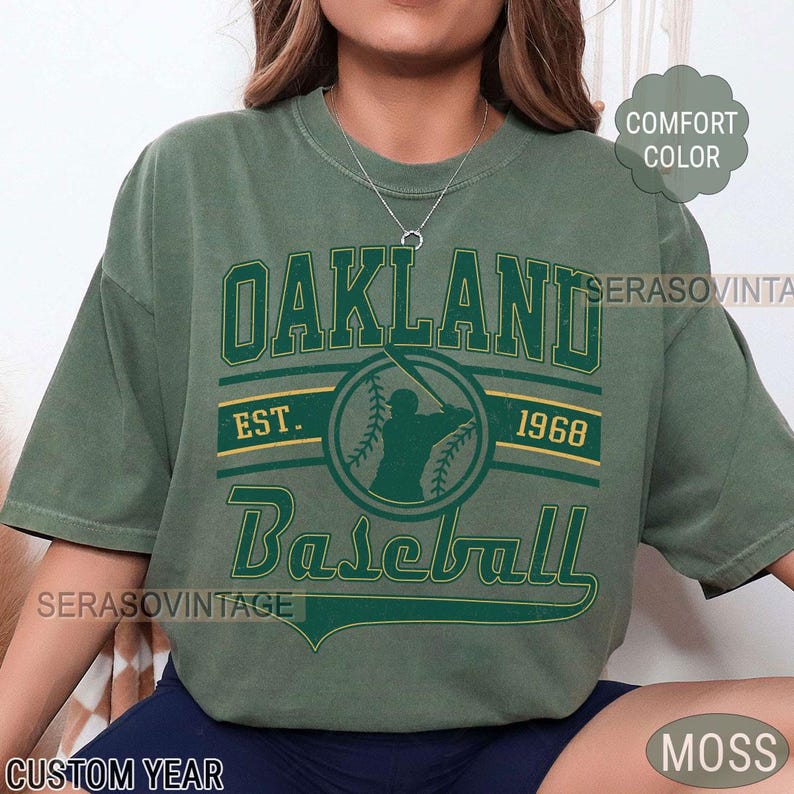 May include: A green t-shirt with a vintage-style graphic of a baseball player and the text "Oakland Baseball Est. 1968".